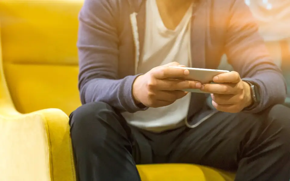 Man holding his phone sideways to play JLBETPH slot and fishing games