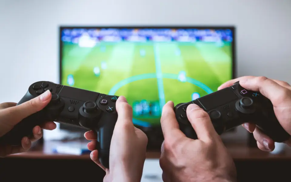 Friends with game controllers watching a football match on a big screen